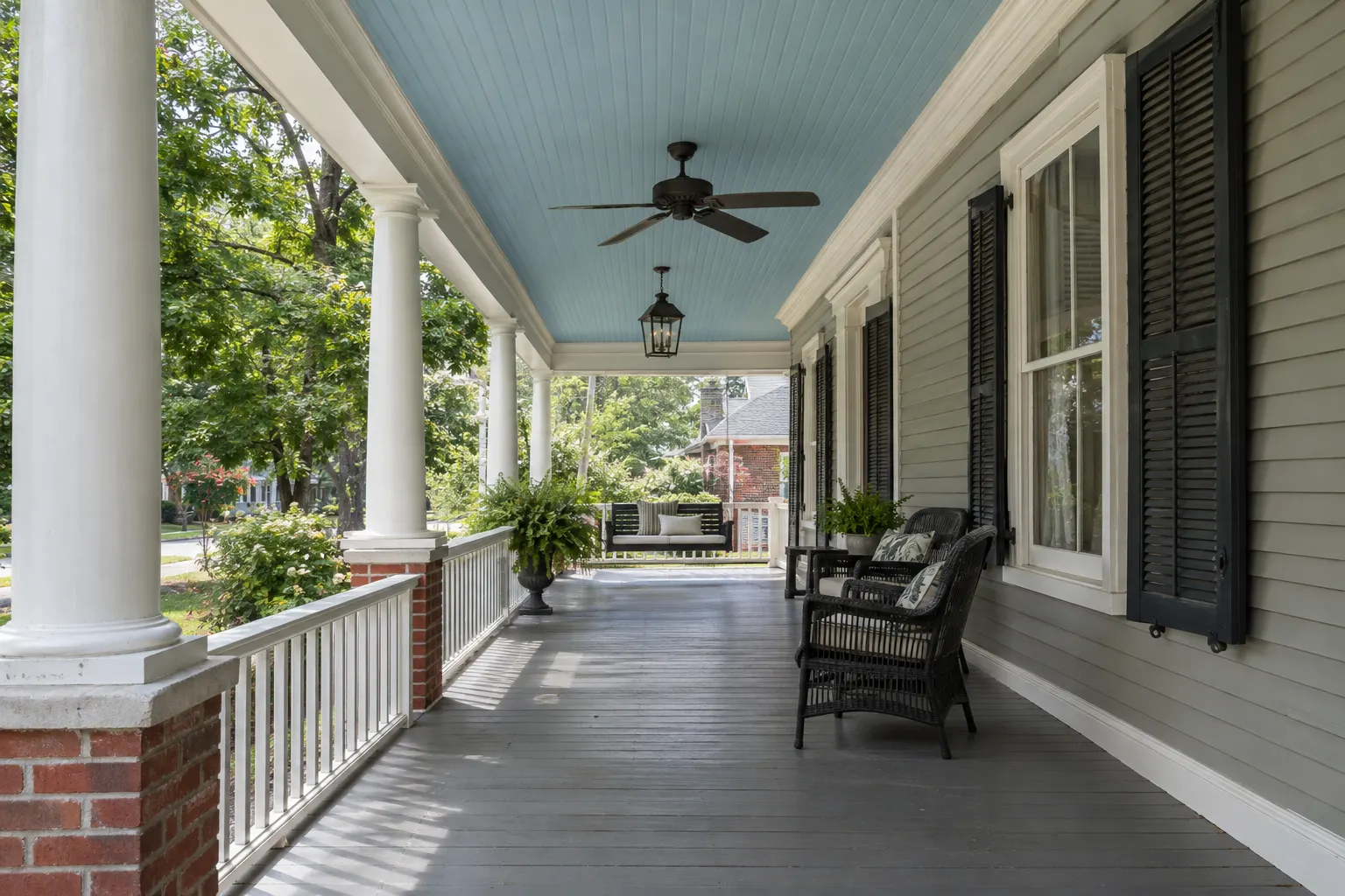 Example image, not one of our jobs: a deep front porch with a pale haint-blue beadboard ceiling, white columns and trim, and grey painted floor boards.